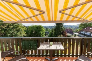 A balcony with a wooden table and chairs, a green shutter, and a view of a residential area. - Eye-catching with a dream view (Braunlage)