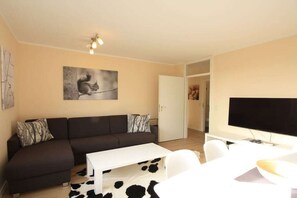 A modern living room with a sofa, a coffee table, and a flat-screen TV. - Holiday apartment with 2 bedrooms (Braunlage)