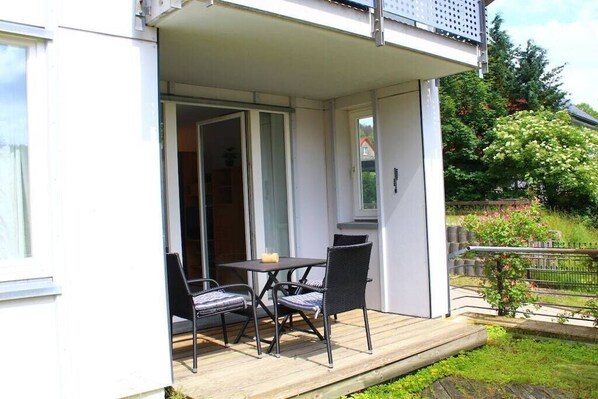 A balcony with a table and chairs, a small plant, and a view of a garden. - Brocken summit with terrace (Schierke)