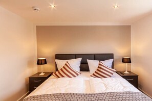 Ein Hotelzimmer mit einem Bett, zwei Nachttischen und einem Kopfteil.