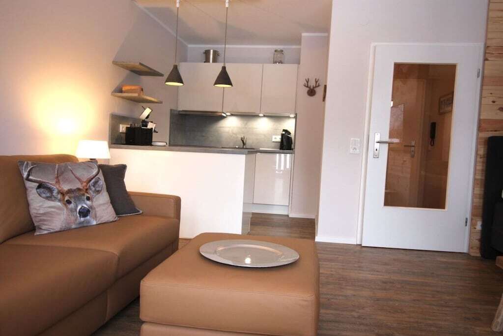 A modern living room with a sofa, a coffee table, and a kitchen in the background.