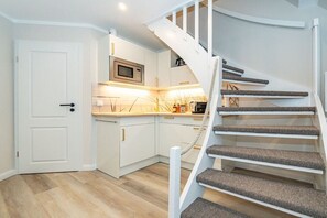 Eine moderne Küche mit weißen Schränken, einer Mikrowelle und einer Holz Arbeitsplatte.