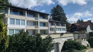 Um edifício residencial de vários andares com varandas, um terraço plano e céu claro.