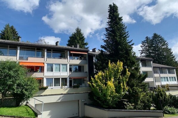 A multi-story residential building with balconies, a garage, and a well-maintained garden. - Holiday apartment with 3 bedrooms (Braunlage)