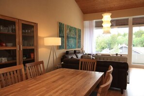A dining area with a wooden table and chairs, a cabinet with glass doors, a floor lamp, and a sofa. - Holiday apartment with 3 bedrooms (Braunlage)