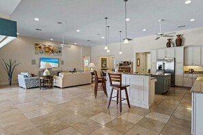 A spacious living area with a kitchen, dining area, and a large island with bar stools. - CCVS - Villa Caribbean Breeze 5* (Cape Coral)