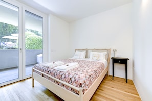 Un dormitorio con cama, mesita de noche, ventana y vistas al exterior.