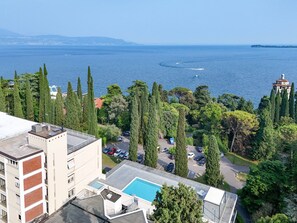 En hög byggnad med en pool på taket, en parkeringsplats och utsikt över havet.