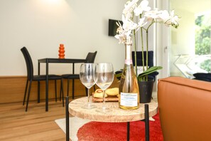 Ein Essbereich mit einem Tisch für zwei Personen, zwei Weingläsern, einer Champagnerflasche und einer Vase mit weißen Blumen.
