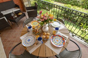A round table set for breakfast with plates, cutlery, and a vase of flowers. - MGH - Tavaredo Lake Retreat, Polpenazze (Polpenazze del Garda)