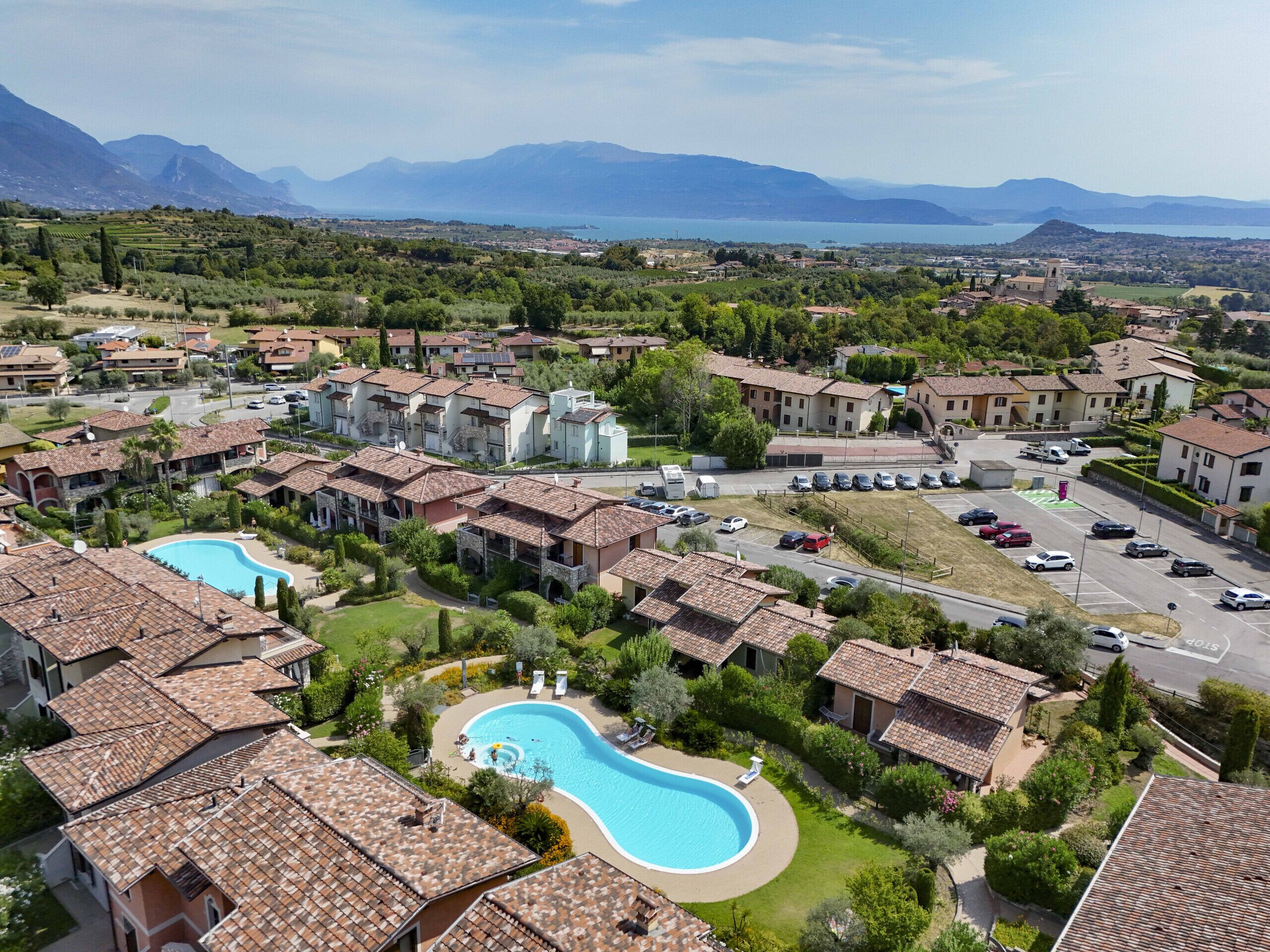 Un quartier résidentiel avec des maisons, une piscine et une vue sur les montagnes et un lac.