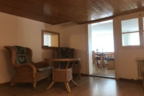 Une pièce dotée d’un parquet en bois, de meubles en osier et d’un grand miroir au mur.