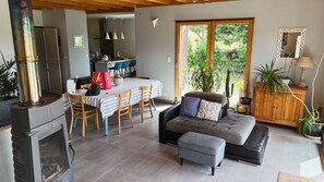 A living room with a sofa, ottoman, and a dining area with a table and chairs. - Bright wooden house with a view of the lake and volcanoes (Aydat)
