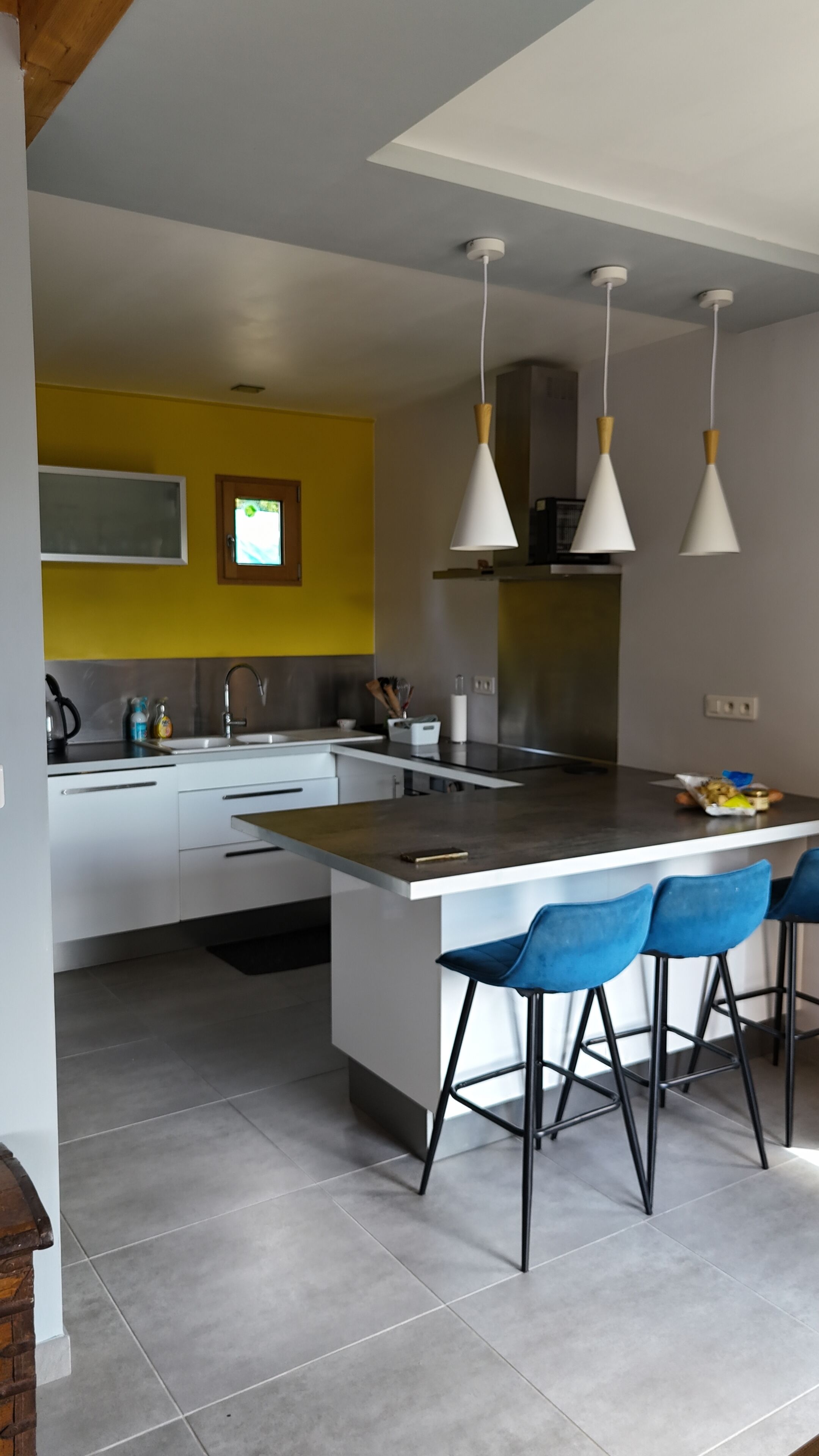 A modern kitchen with a central island, bar stools, and pendant lighting.