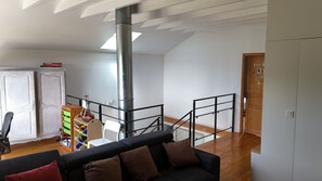A spacious living area with a black sofa, wooden flooring, a staircase, and a white wardrobe. - Bright wooden house with a view of the lake and volcanoes (Aydat)