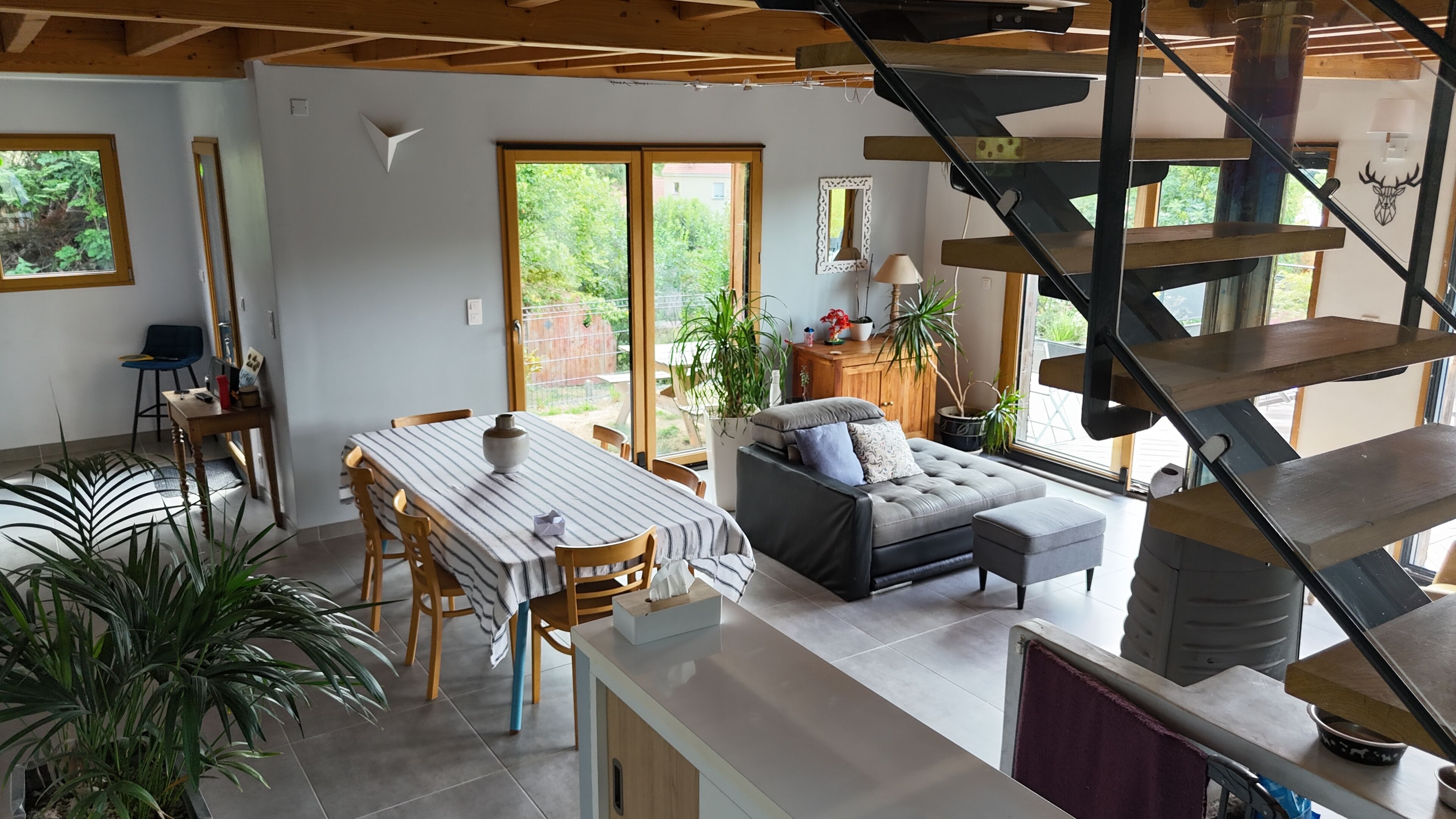 Een ruime woonkamer met een eettafel, bank en trap.