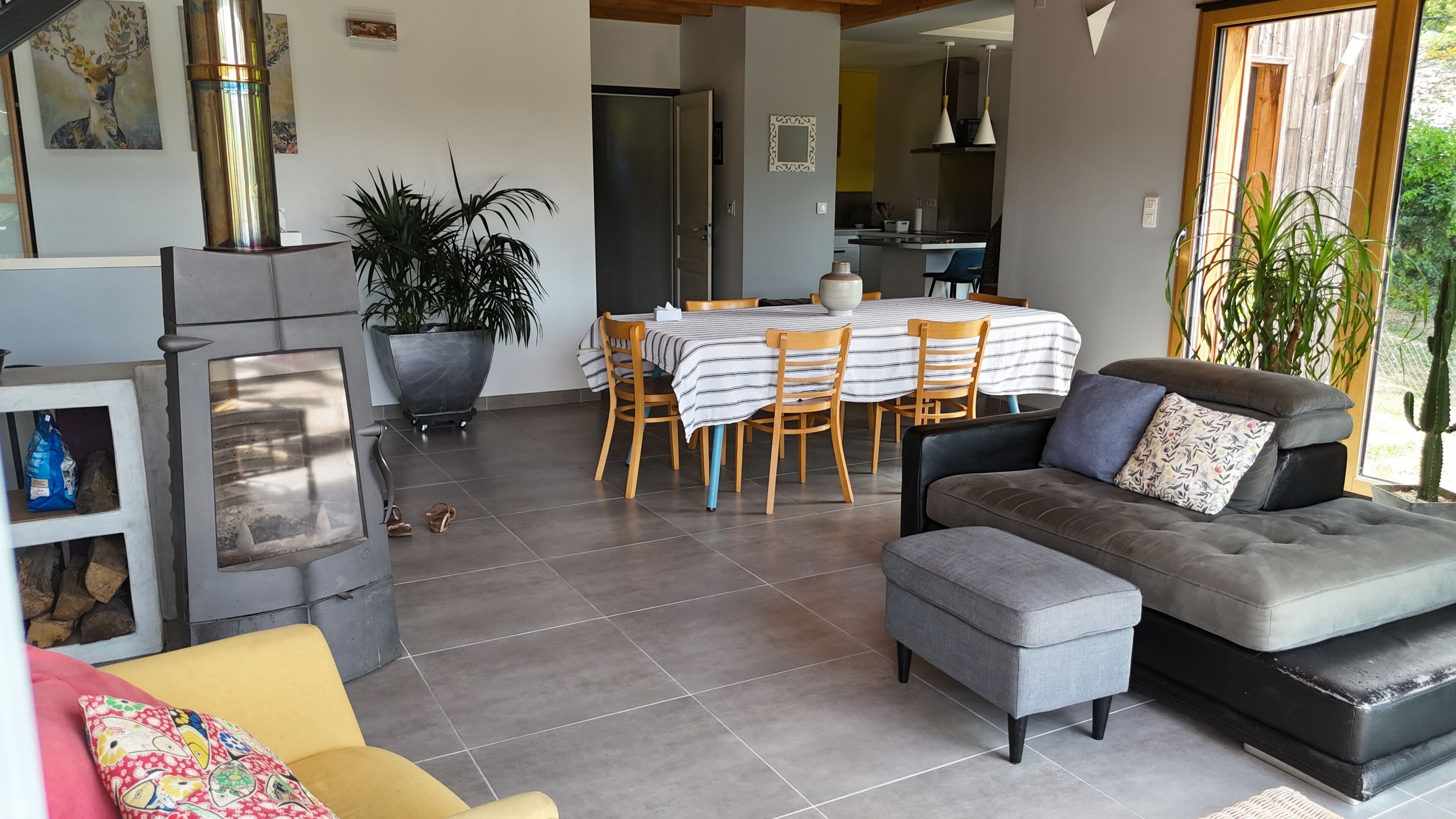 Ein modernes Wohnzimmer mit einer Couch, einem Hocker und einem Essbereich mit Tisch und Stühlen.