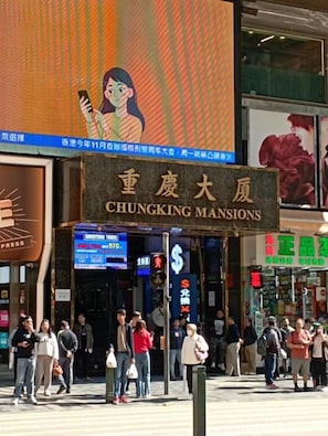 A busy street with a prominent sign for 'CHUNGKING MANSIONS'. - Everest Base Camp (Kowloon)
