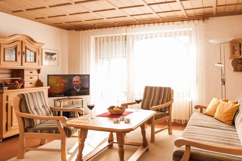A living room with a television, wooden furniture, a sofa, and a dining table.