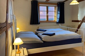 Een slaapkamer met een bed, twee bedlampen, een raam met gordijnen en een radiator.