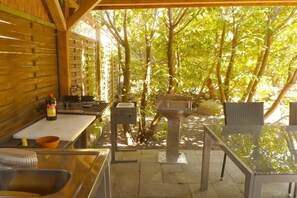 An outdoor kitchen area with a grill, a sink, and a table. - Holiday apartment in Wiek with Wi-Fi (Wiek)