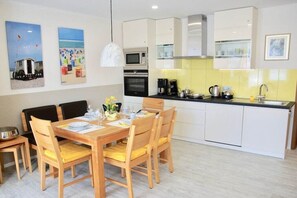 A compact kitchen with white cabinets, a microwave, and a coffee maker. - Holiday apartment with 1 bedroom (Norderney)