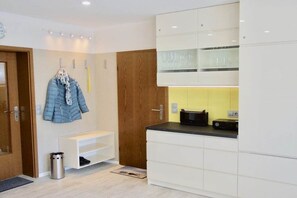A modern kitchen with white cabinets, a black countertop, and a yellow backsplash. - Holiday apartment with 1 bedroom (Norderney)