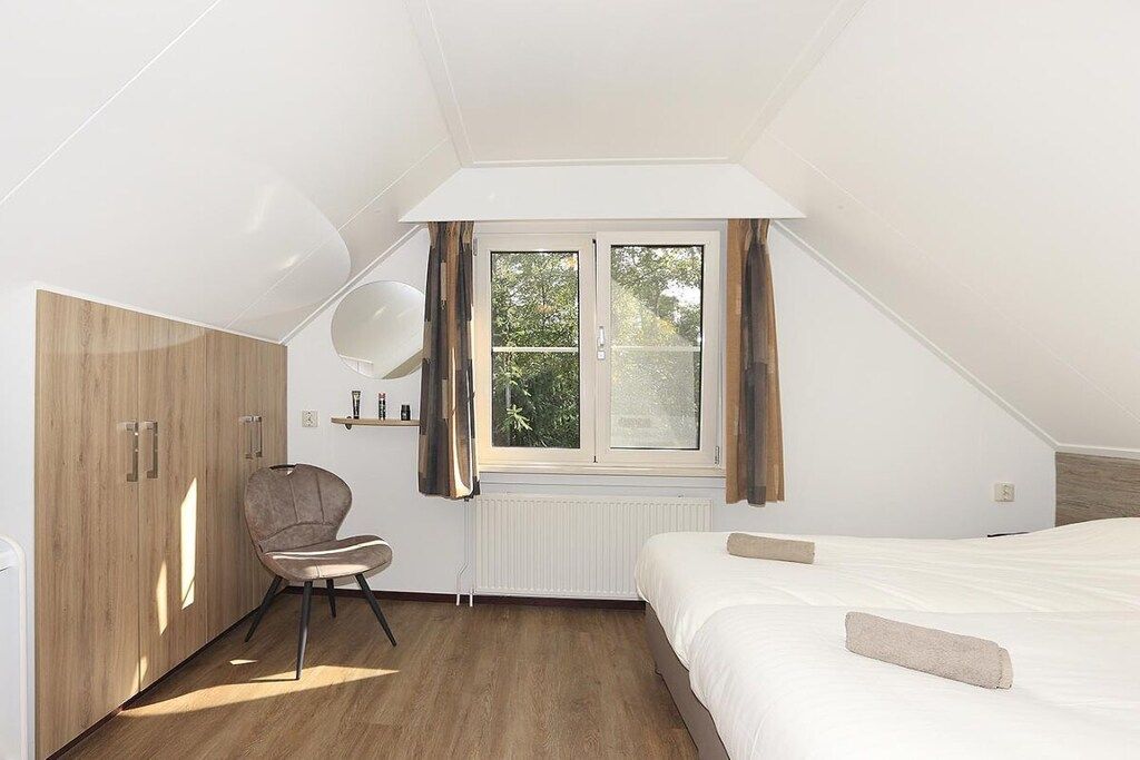 Ein Schlafzimmer mit einem Bett, einem Sessel, einem Kleiderschrank, einem Fenster und einer Heizung.