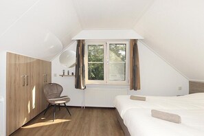 A bedroom with a bed, a chair, a wardrobe, a window, and a radiator. - Wellness Superior 6/8-P (DEURNINGEN)