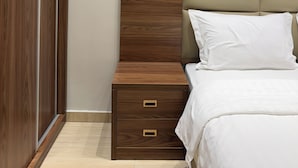 A bedroom with a wooden nightstand, a bed with a headboard, and a wardrobe. - Alamaan Servised Apartment  (Madinah)