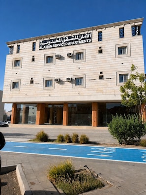 A multi-story building with a sign indicating it is serviced apartments.