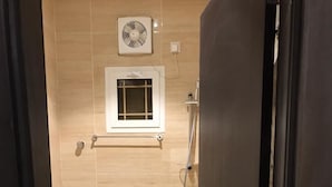 Ein Badezimmer mit Toilette, Dusche und einem Wandventilator.