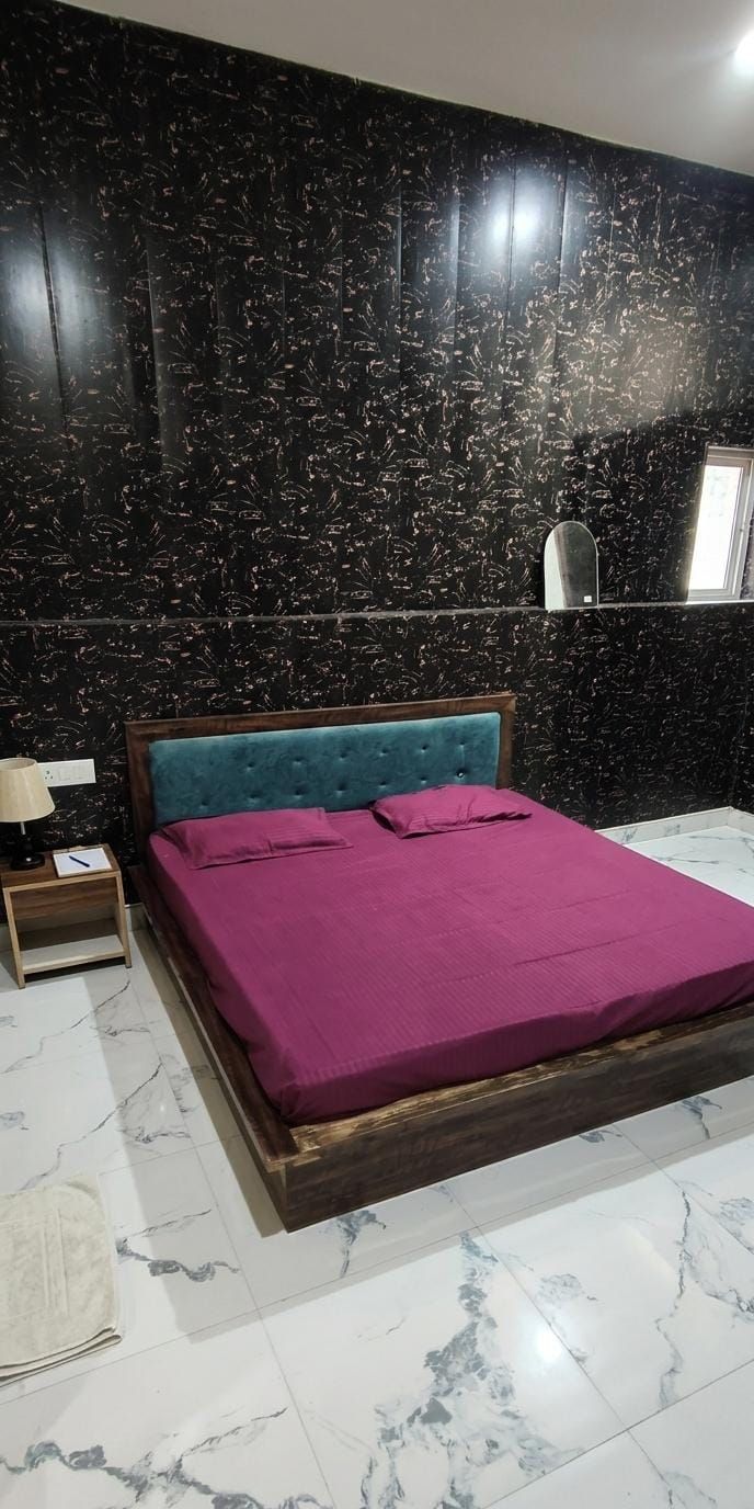A bedroom with a bed, a nightstand, a mirror, and a window.