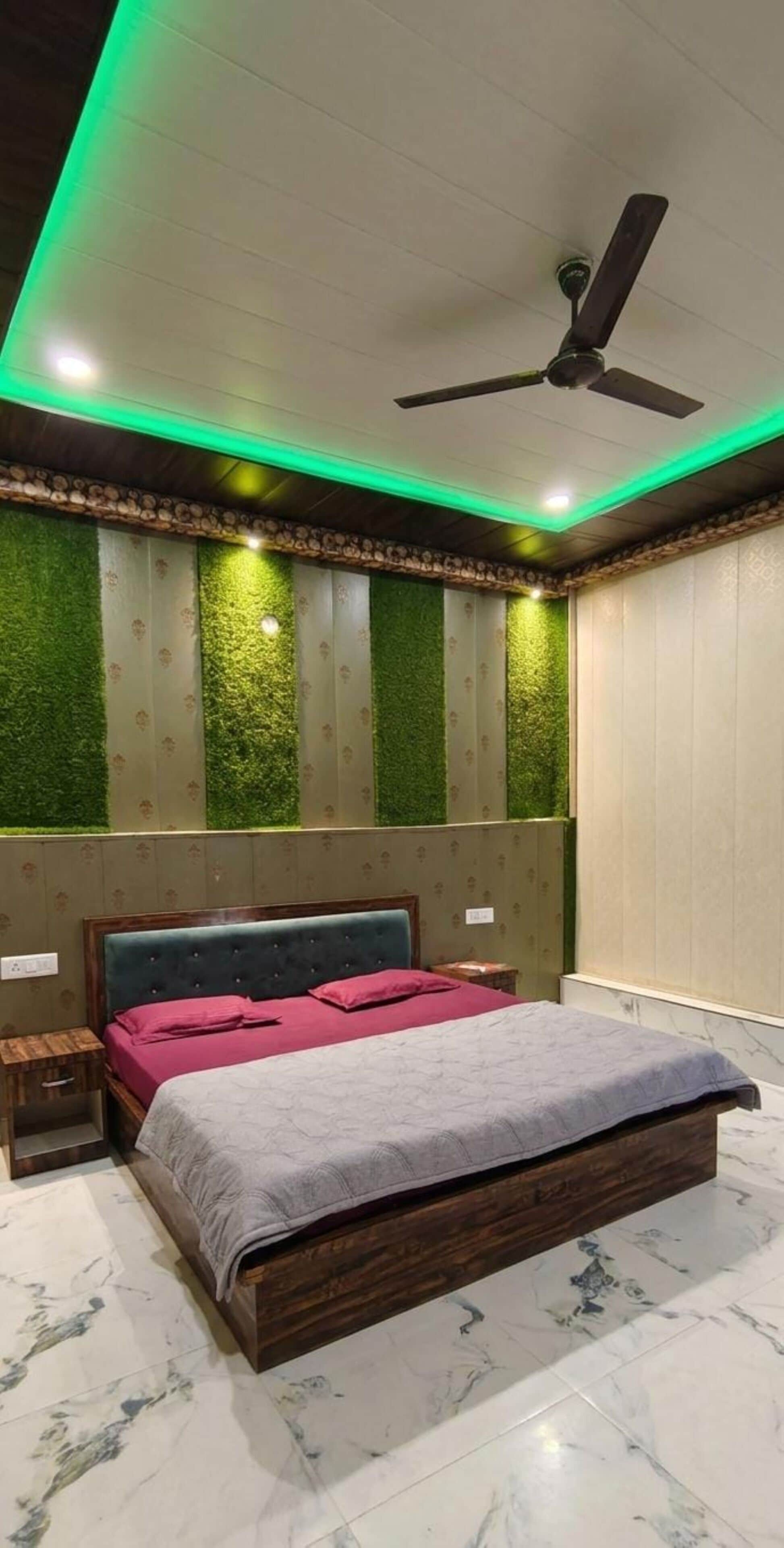 A bedroom with a bed, a nightstand, a ceiling fan, and green wall panels.