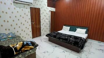 A bedroom with a bed, a bedside table, a wardrobe, and an air conditioning unit.