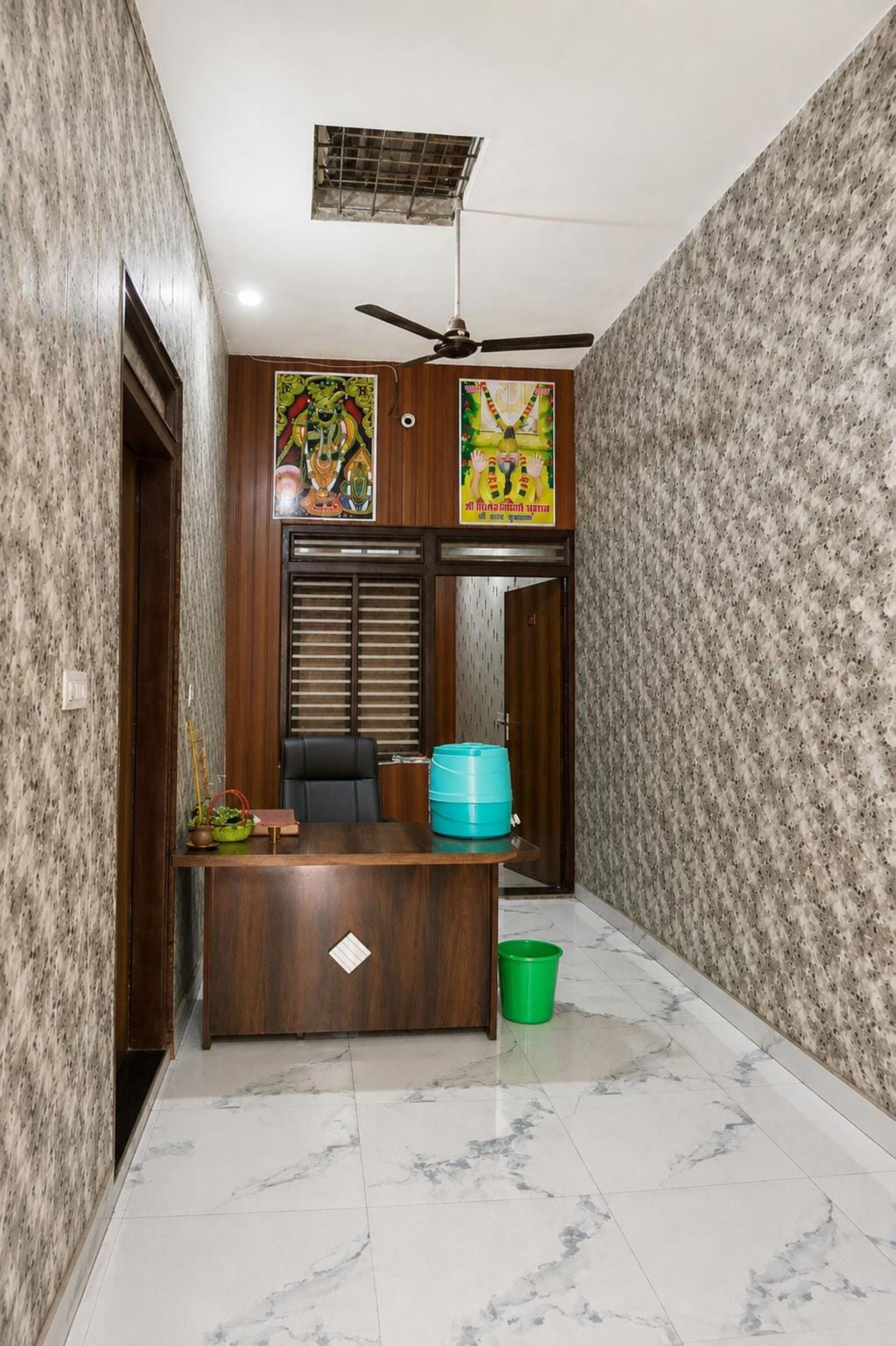 A hallway with a desk, a ceiling fan, and a door.