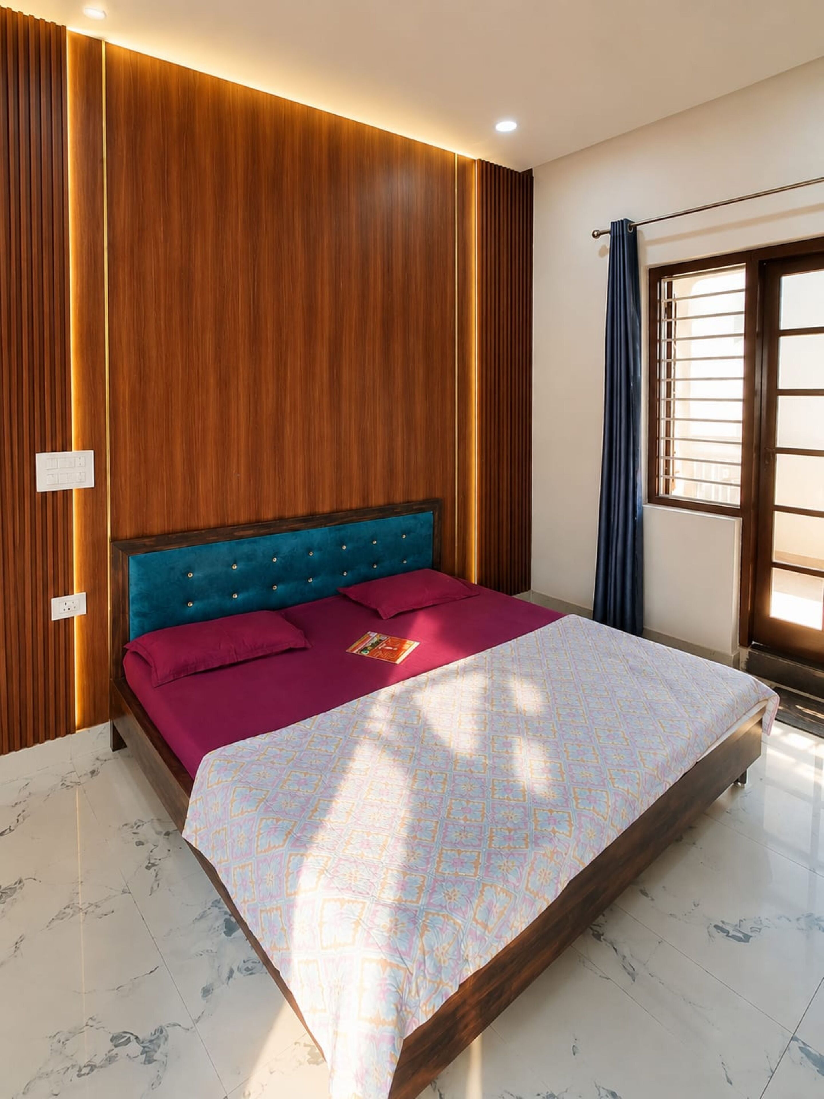 Un dormitorio con cama, paredes de paneles de madera, una ventana con cortinas y suelo de mármol.