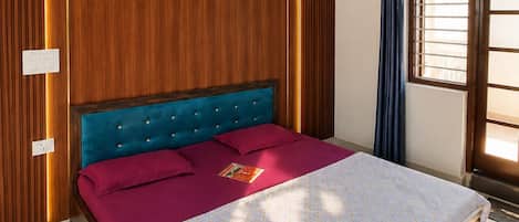 A bedroom with a bed, wooden panel walls, a window with curtains, and a marble floor.
