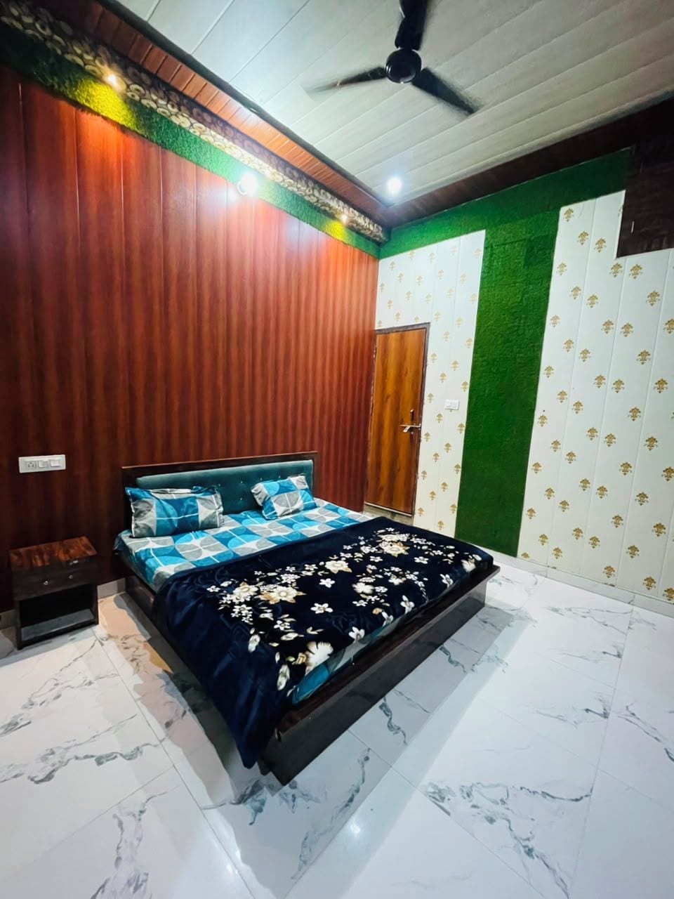 Un dormitorio con cama, ventilador de techo, puerta y pared verde.