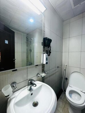 Un baño con lavamanos, inodoro, espejo y zona de ducha.