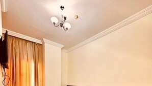 Habitación de hotel con dos camas, un candelabro y un televisor.