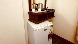 Una kitchenette compacta con refrigerador, microondas y cafetera sobre una pequeña mesa.