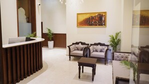 A reception area with a desk, two sofas, a coffee table, and a chandelier. - Kashi Courtyard (Varanasi)