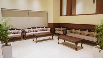Un salón de conferencias con una pizarra grande, varios sofás y mesas de madera.