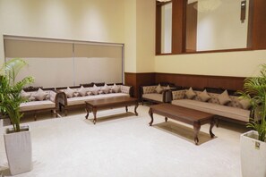 Un salón de conferencias con una pizarra grande, varios sofás y mesas de madera.