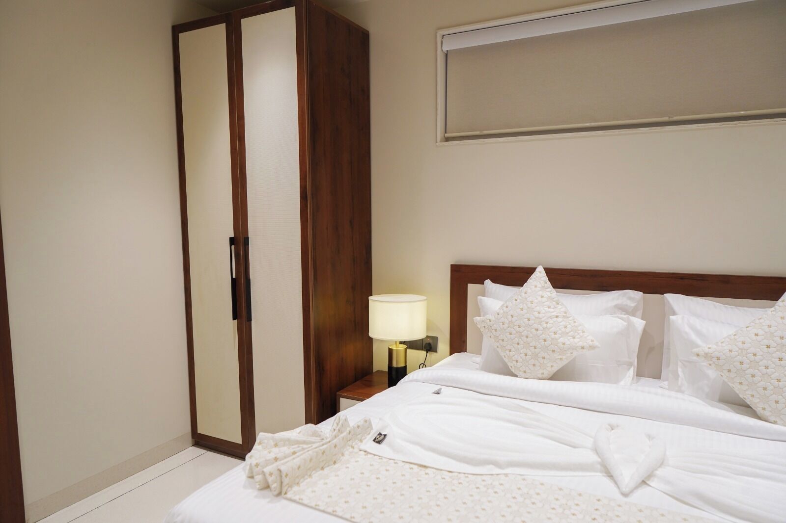 Een hotelkamer met een bed, een garderobe en een nachtkastje met een lamp.