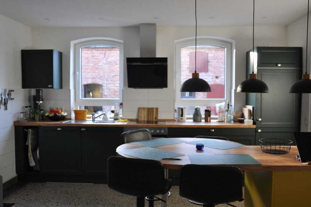Una cucina moderna con isola centrale, due luci a sospensione e un televisore a schermo piatto montato sopra l'isola.