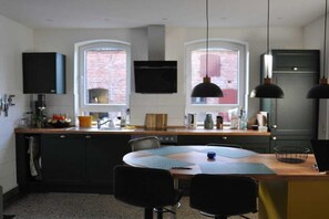 A modern kitchen with a central island, two pendant lights, and a flat-screen TV mounted above the island. - Holiday home with 4 bedrooms (Gorlosen , OT Strassen)