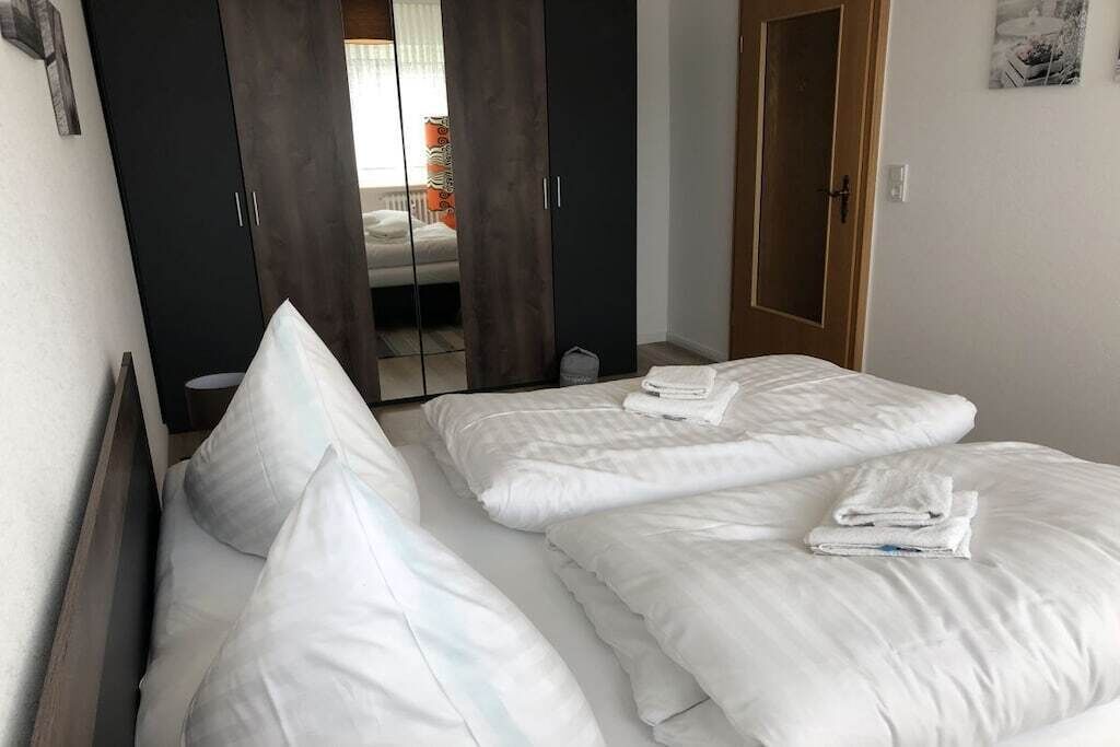 A hotel room with two beds, a wardrobe, and a door leading to a bathroom.