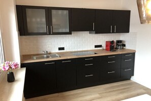 A kitchen with black cabinets, a wooden countertop, a sink, and a coffee maker. - Holiday apartment with 1 bedroom (Hahnenklee Bockswiese)